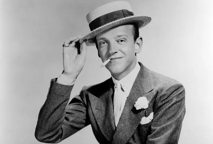 Fred Astaire w garniturze poszetką, kwiatkiem w butonierce i w kapeluszu